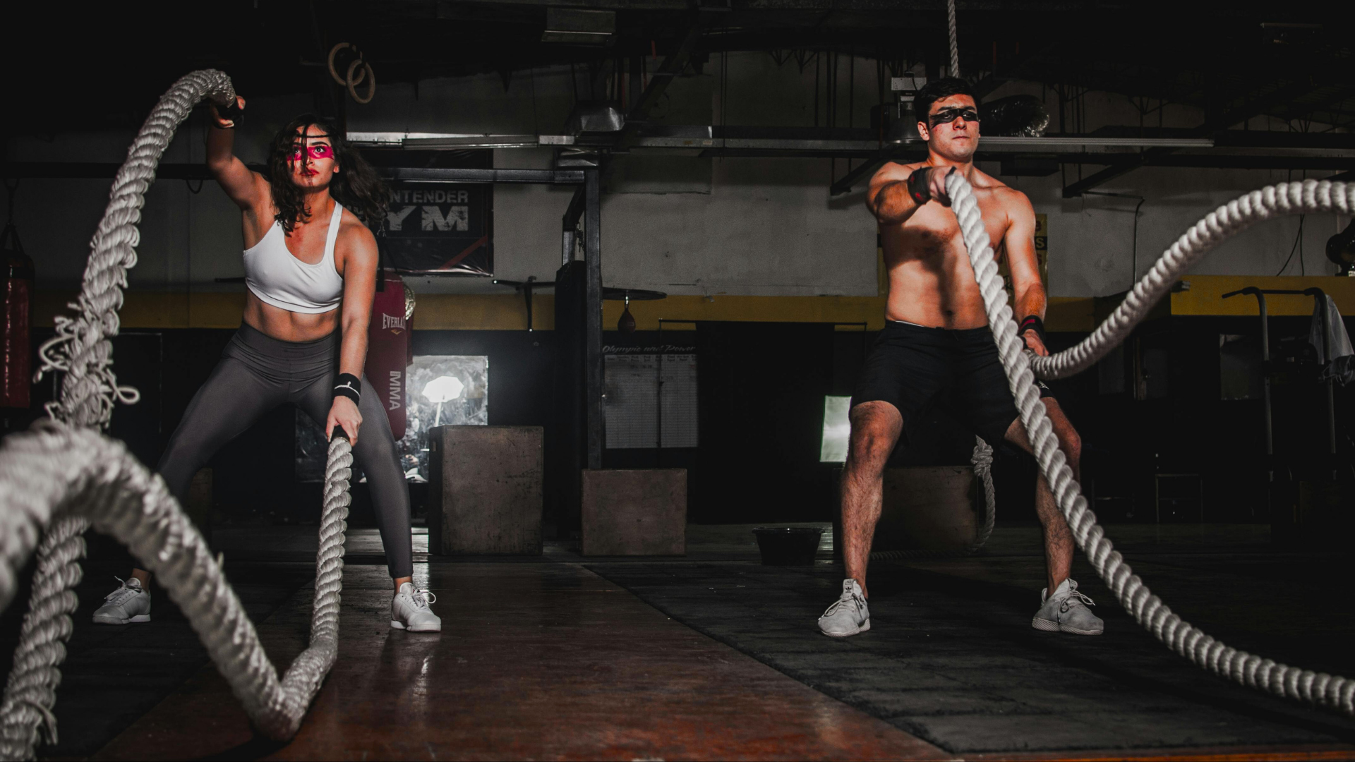 Two parents training with battle ropes in a fitness studio, building strength and resilience.
